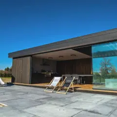 Nowoczesna altana z kuchnią i tarasem. Podłoga z płyt betonowych, idealna do stworzenia strefy relaksu.